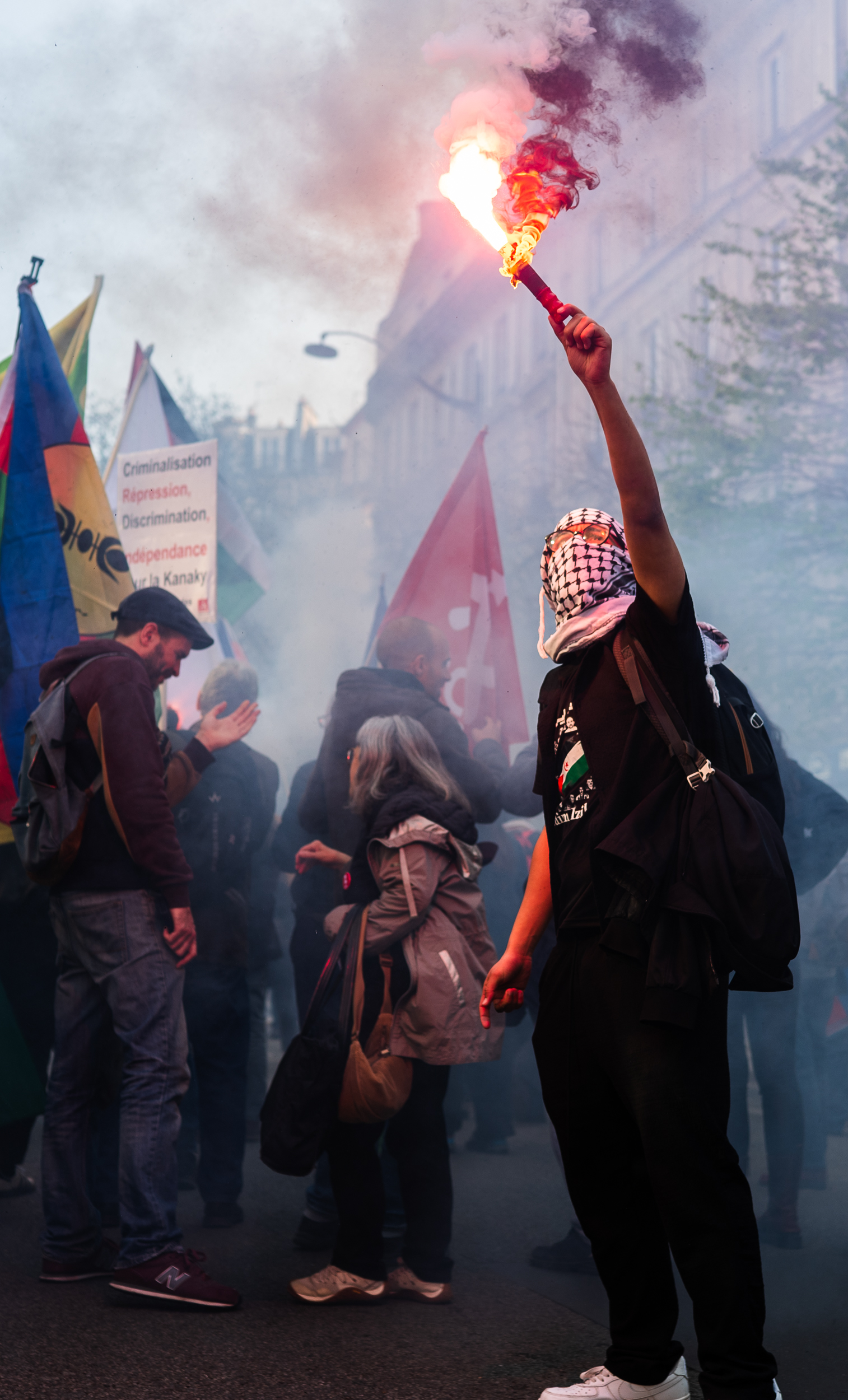Protester holding a lit flare in a smoky street.